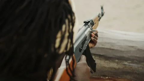 Unrecognizable black man with head covering pulling triger of AK-47 Video stock 142144227