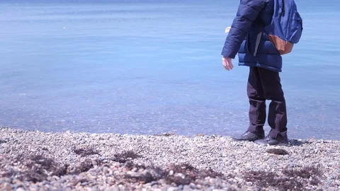 Unrecognizable boy feeding pigeons in winter at rocky beach on sea backround. Stock Footage 116464724