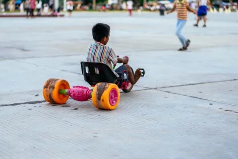 Unrecognizable boy with his back turned in the park driving a toy car before the Stock Photos