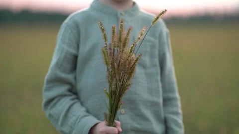 Unrecognizable boy presents bunch of wild plants in open field  Stock-Footage 342967279