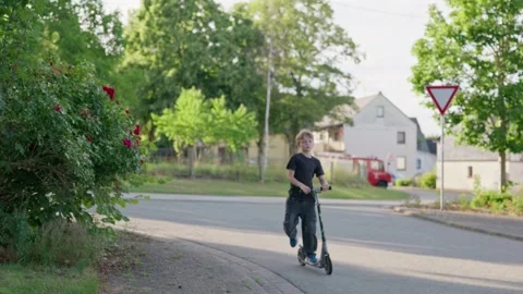 Unrecognizable Boy Riding Kick Scooter in Village 스톡 동영상 345710510
