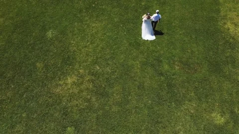 Unrecognizable bride and her dad walking across a grass field at a wedding. Stock Footage 201575282