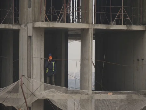 Unrecognizable builder talks on cellphone at construction site. Handheld shot Stock Footage 85053900