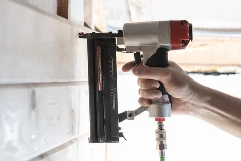 Unrecognizable builder worker hand using pneumatic stapler for wooden board.. Foto stock