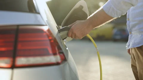 Unrecognizable businessman plugging in charging cable to to electric vehicle Stock Footage 200975064
