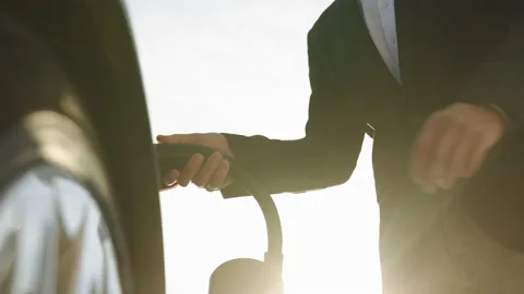 Unrecognizable businessman plugging in charging cable to to electric vehicle Stock Footage 220322416