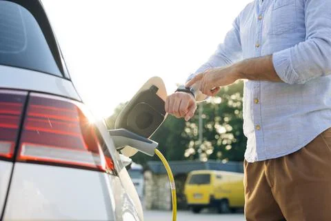 Unrecognizable businessman plugging in charging cable to to electric vehicle Stock Photos