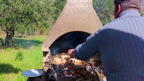 An Unrecognizable Calabrian Turns Bread on a Grill Outside the City. Stock Footage 236936101