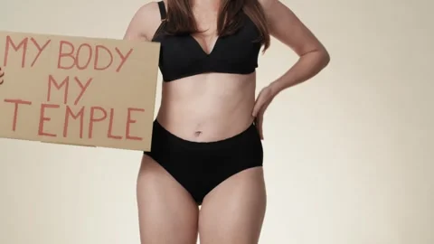 Unrecognizable caucasian woman in underwear dancing with a banner in the studio