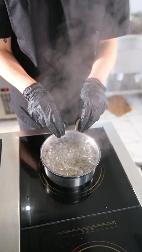 Unrecognizable chef in black gloves and uniform placing fresh dumplings into a Stock Footage 318317034