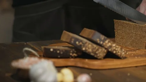 Unrecognizable chef cuts black bread on slices or sticks to prepare beer snacks Stock Footage 94590178