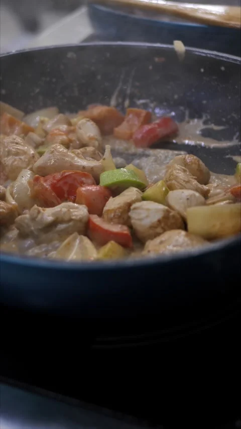 Unrecognizable chef frying vegetables and meat on a hot frying pan while cooking Stock Footage 306746976