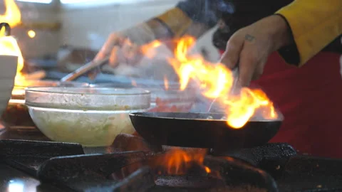 Unrecognizable chef holding two pans and cooking flambe style dish in kitchen Stock Footage 299547115