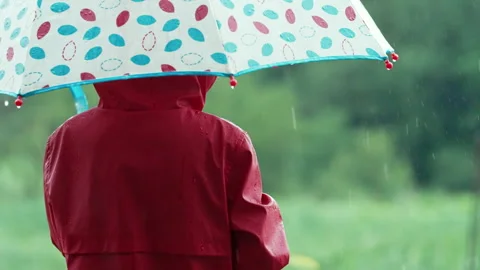 Unrecognizable child boy with umbrella under rain. Kid in red raincoat enjoying. Stockbeeldmateriaal 279394122
