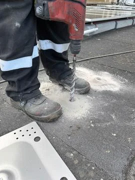 Unrecognizable construction worker making a hole in the concrete floor with a Stock Photos