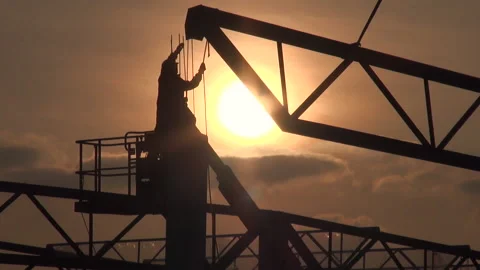 Unrecognizable construction worker placing steel roof frame at sunset. Stock Footage 144694523