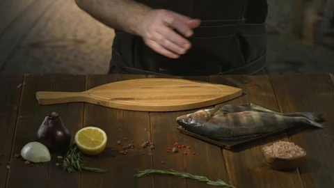 Unrecognizable cook or chef puts fresh fish on cutting board for salting Stock Footage 94585768