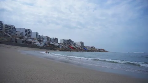 An unrecognizable couple in love playing with the waves of the sea in the Stock Footage 195125895