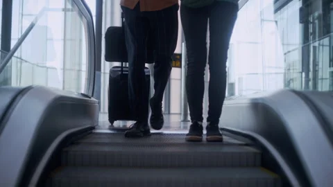 Unrecognizable Couple with luggage riding escalator in airport Stock Footage 334566053
