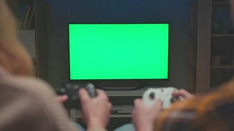 Unrecognizable Couple Playing Console Video Game in Front of Big Green Screen Vidéo 336940811