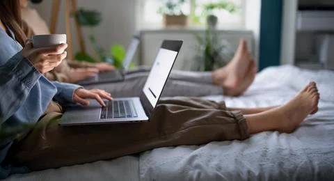 Unrecognizable couple using laptops on bed indoors, home office concept. Fotos Stock