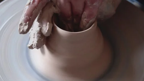 Unrecognizable craftsman wetting hands and shaping clay pot on spinning wheel Stock Footage 143614906