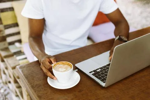 Unrecognizable cropped multicultural man using laptop, taking notes in workbook Stock Photos