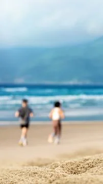 Unrecognizable distant couple walking along a sandy ocean beach on a warm s.. Stock Photos