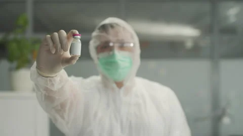 An unrecognizable doctor in a bacteriological protective suit holds a close-up Stock Footage 150333703
