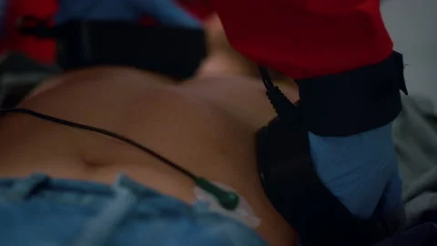 Unrecognizable EMS paramedic hands making cpr with defibrillator on patient body Stock Footage 166885981