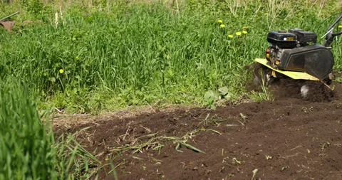 Unrecognizable farmer plows arable land with rotary mini tiller, slow motion Stock Footage 202136849