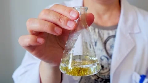 Unrecognizable female chemist technician hand shaking flask with golden glitter Stock Footage 254393782
