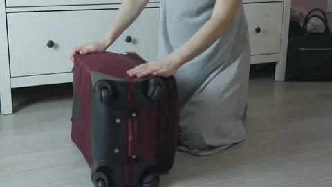 Unrecognizable female hands checking red suitcase on floor home ready to go Stock Footage 170937541