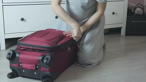 Unrecognizable female hands packing red suitcase putting clothes on floor room Stock Footage 171190189