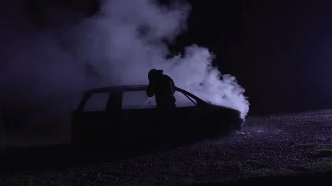 Unrecognizable fireman combating a fire of a burning car accident. Firefighter Stock Footage 261977786