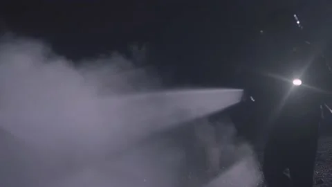 Unrecognizable fireman silhouette combating a fire of a burning car accident at Stock Footage 234974098