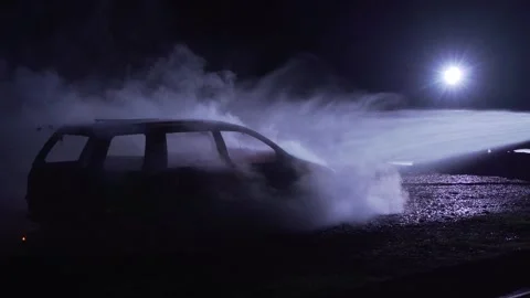 Unrecognizable fireman silhouette combating a fire of a burning car accident Stock-Footage 261977747