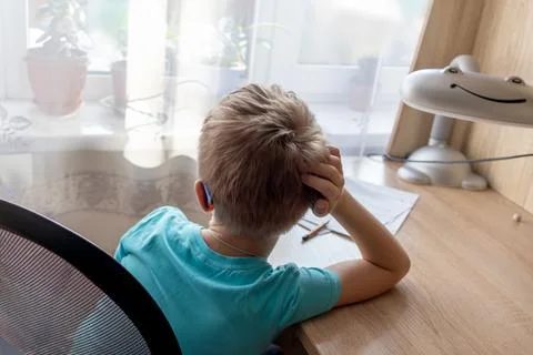 Unrecognizable first-grade boy can't bring himself to do his homework, dayd.. Stock Photos