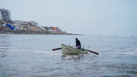 An unrecognizable fisherman rowing looking back worried about something he saw Vidéo 195126262