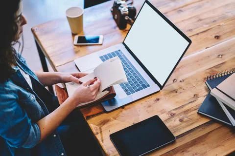 Unrecognizable freelancer with textbook using blank netbook with copy space area Stock Photos