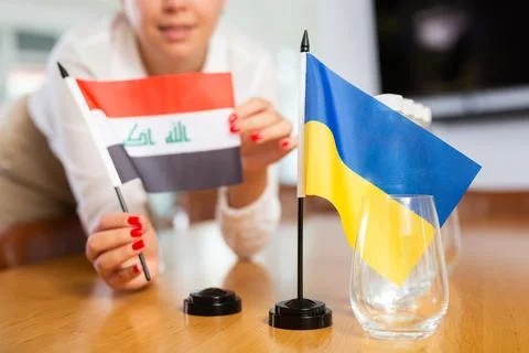 Unrecognizable girl sets midget flags of Ukraine and Iraq before international Stock Photos