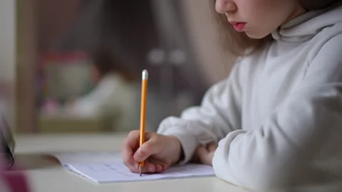 An unrecognizable girl sits at a table, on which the tablet sits, and writes Stock Footage 269327973