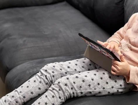 Unrecognizable girl sitting on the sofa using a tablet Stock Photos