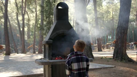 Unrecognizable guy stand in forest and look at fire in stove. small man stand on Stock Footage 229901743