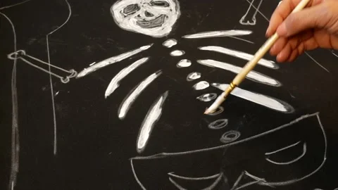 Unrecognizable hand draws a picture of a skeleton on black cloth with a brush Video stock 162769290