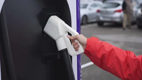 Unrecognizable hand grasping the hose with the plug of an electric vehicle Stock Footage 254861246
