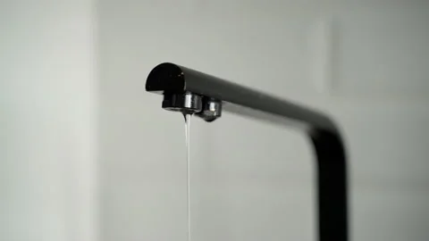 An unrecognizable hand open the tap. Water flows in a thin small stream Stock Footage 153284098