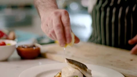 Unrecognizable hand prepare dish with fish, squeezing lemon juice onto the dish. Stock-Footage 336588884