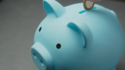 Unrecognizable hand puts coins in blue piggy bank. Save money for your dream. Stock Footage 342593626