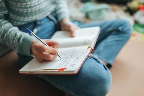 Unrecognizable hand writes notes or to-do list in diary notebook. Stock Photos